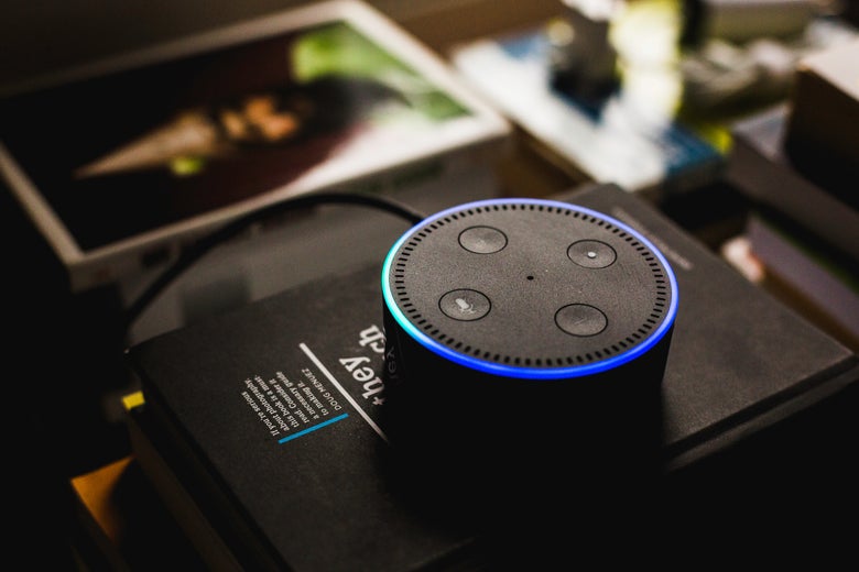 An Echo dot sits on a pile of books.